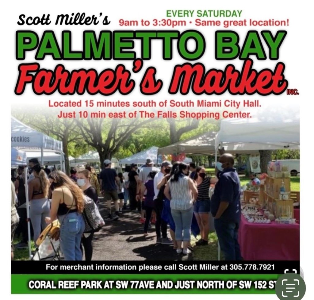 A bustling farmer's market scene at Coral Reef Park, with a crowd of people browsing stalls filled with fresh produce and homemade goods. Canopies provide shade as people enjoy the sunny day.